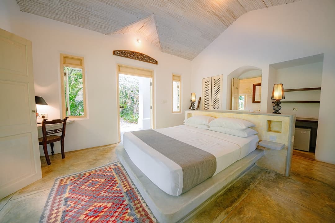 Rivers Edge bedroom with white king bed and woven rug