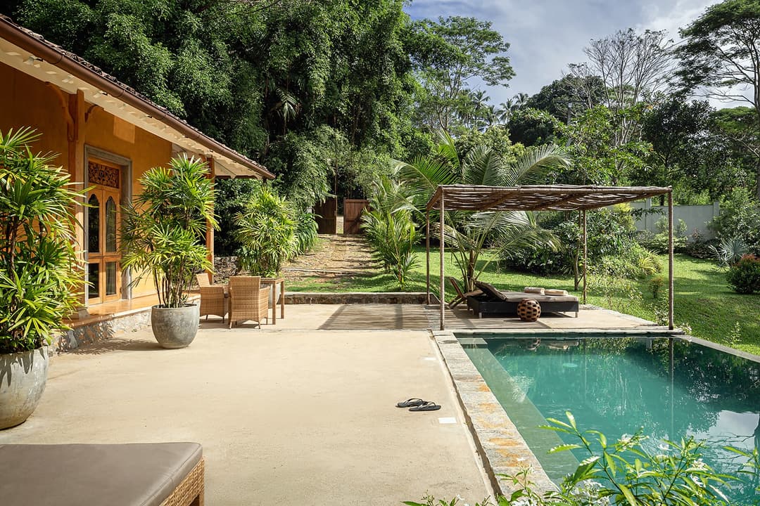 Kahanda Kanda infinity pool with thatched roof under blue sky