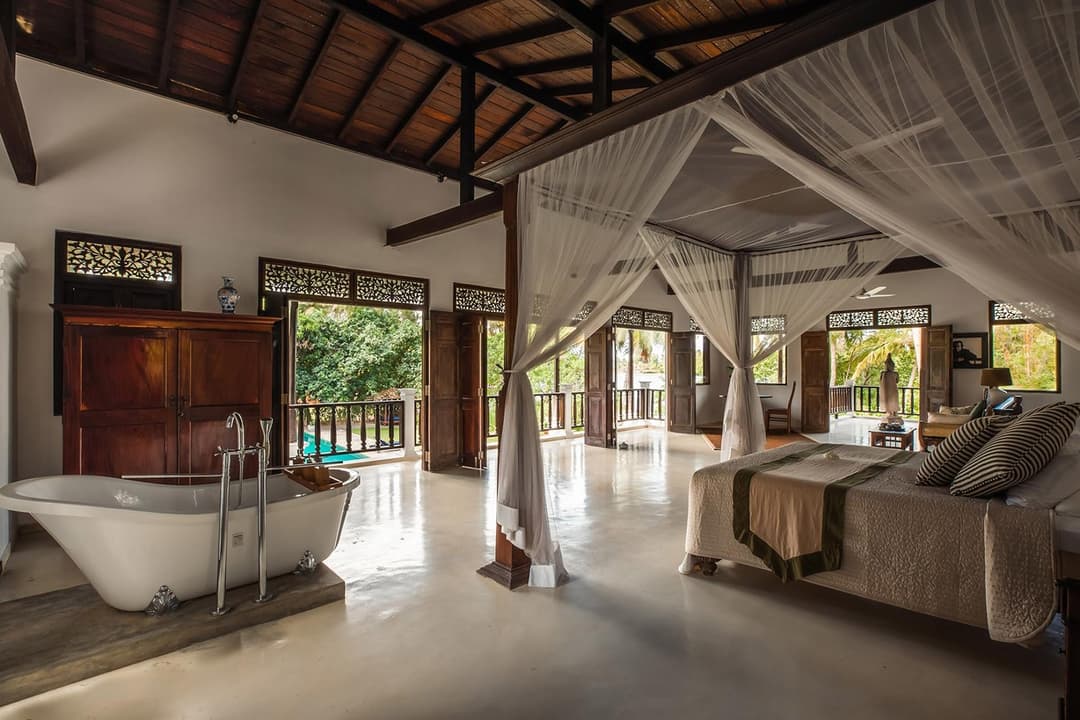 Master bedroom with wide timber floors, antique furnishings and garden outlook, Casa Lago, Koggala