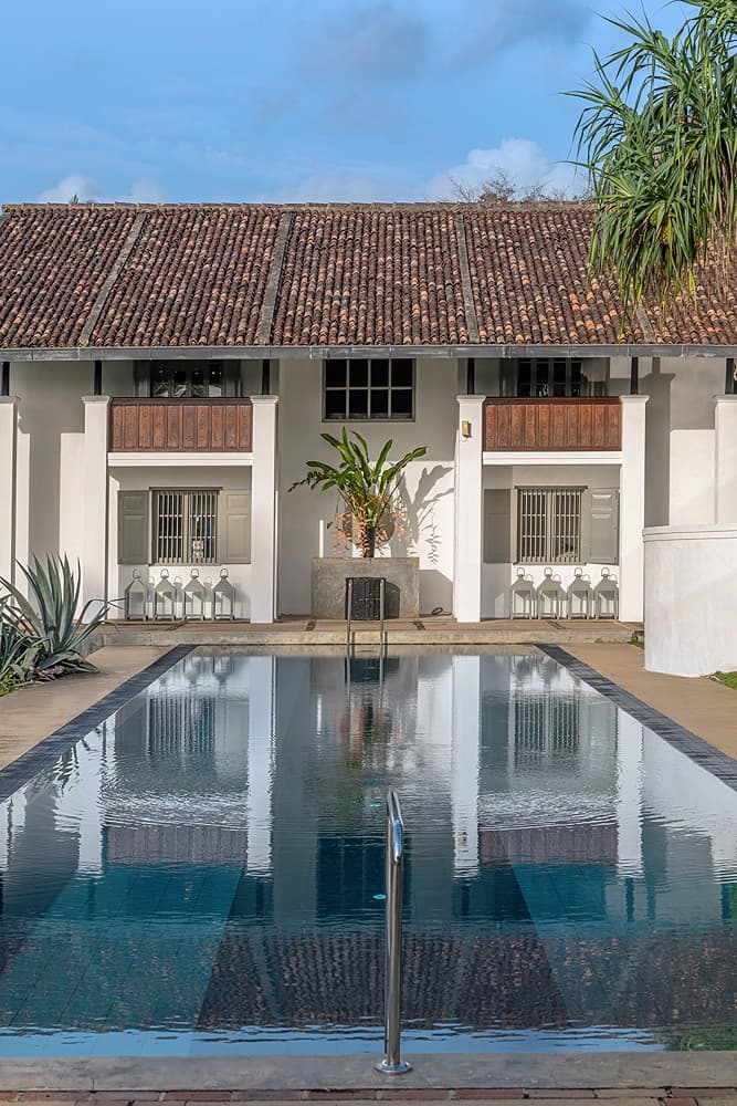 Long view of Heritage House Bentota pool with tropical garden and sun loungers, Bentota