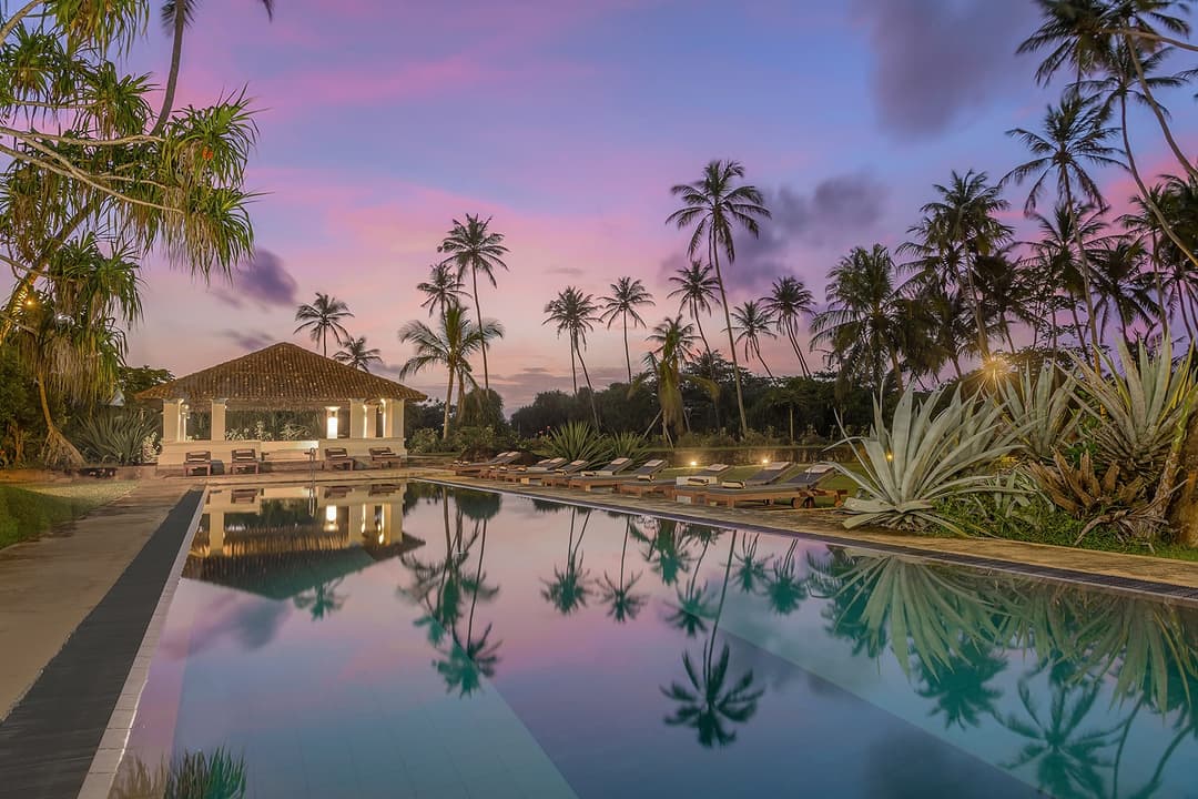 Heritage House Bentota pool at dusk under a vivid purple sky with palm silhouettes