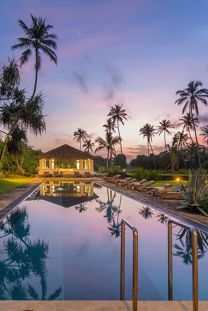 Heritage House Bentota pool at dusk with illuminated palms and colonial building reflected