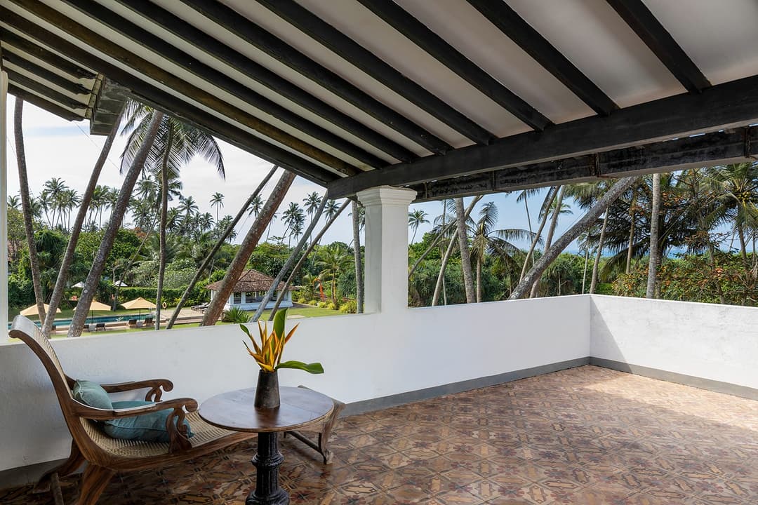 Private terrace with rattan chairs overlooking tropical garden at Heritage House Bentota
