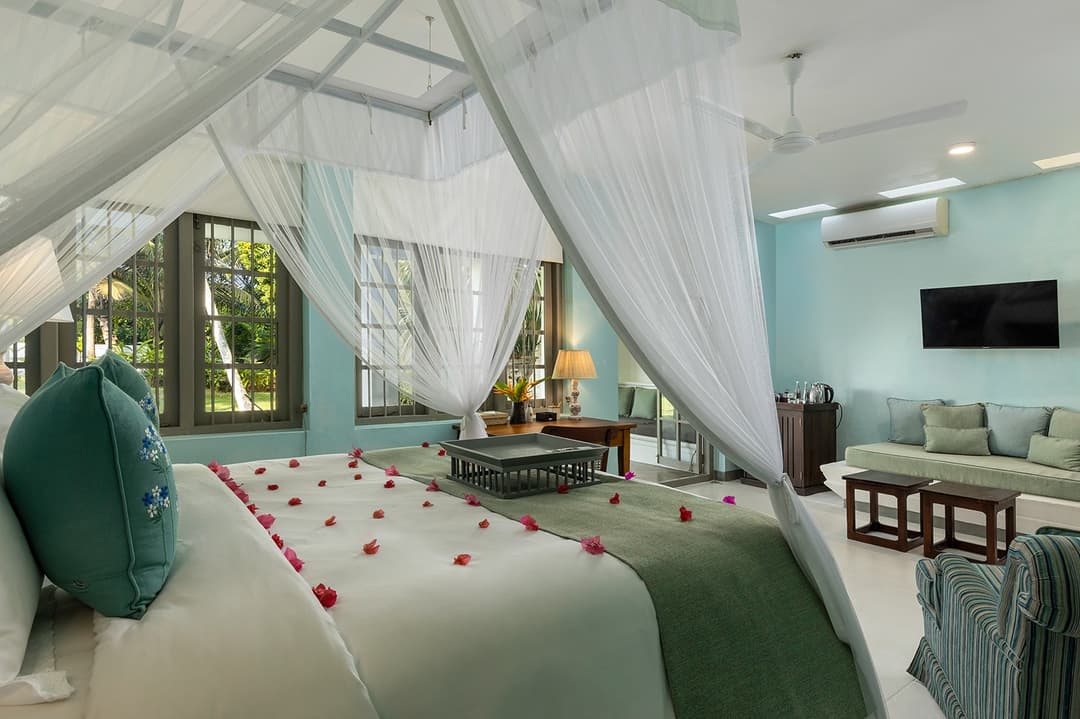 Teal bedroom with canopy bed and sitting area at Heritage House Bentota, Bentota, Sri Lanka