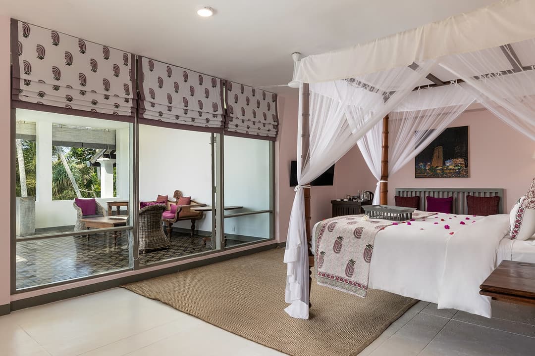 Coral-toned four-poster bedroom with draped netting at Heritage House Bentota, Sri Lanka