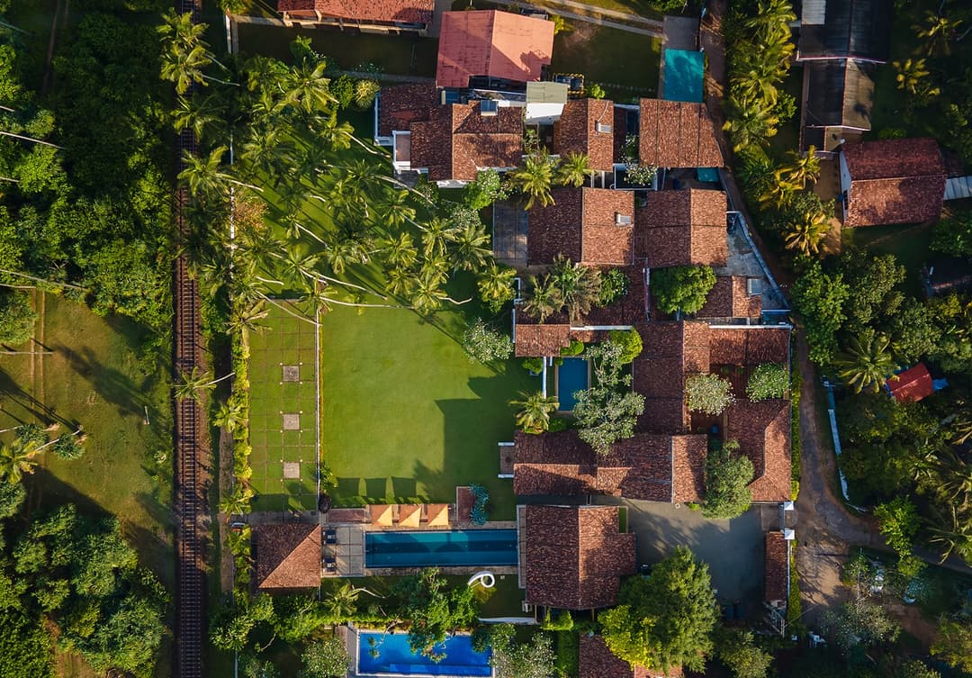 Aerial showing Heritage House Bentota, tropical gardens and Indian Ocean beach beyond railway