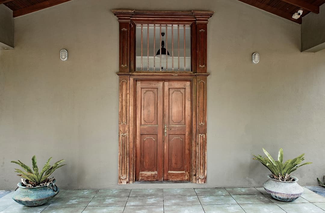 Carved timber entrance door with tropical planting at Cottage Kabalana, Ahangama, Sri Lanka