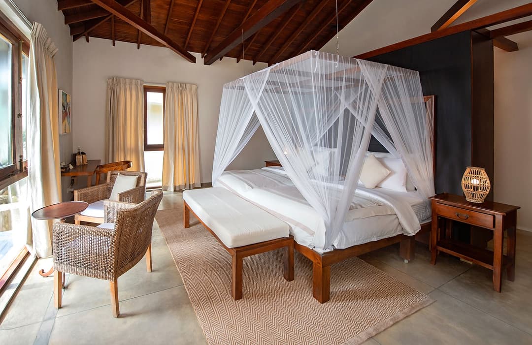 Bedroom with vaulted ceiling, canopy bed and rattan chairs at Cottage Kabalana, Ahangama