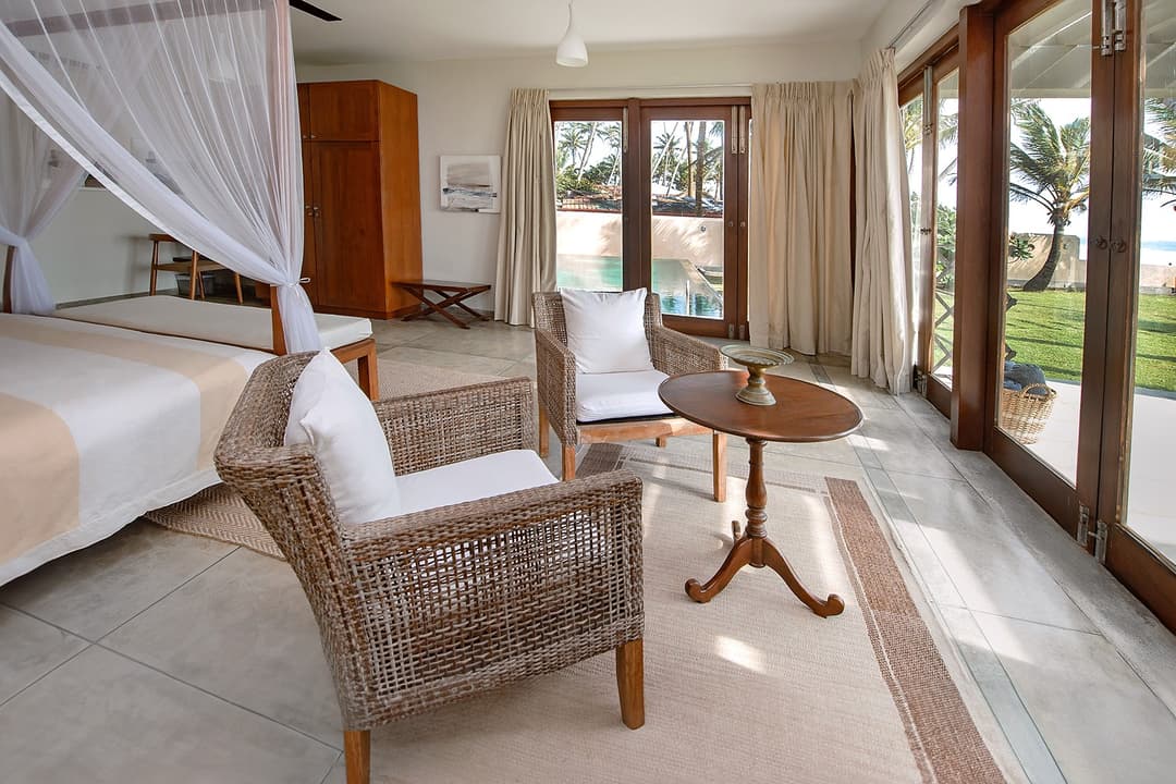 Bedroom with louvred doors open to garden and beach at Cottage Kabalana, Ahangama