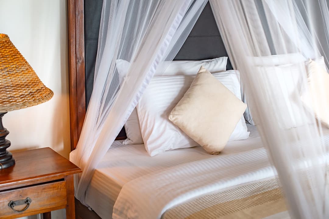 Four-poster canopy bed with cushion detail at Cottage Kabalana, Ahangama, Sri Lanka