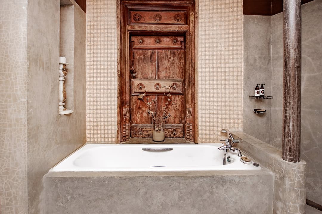 Stone shower room with carved timber door at Cottage Kabalana, Ahangama, Sri Lanka