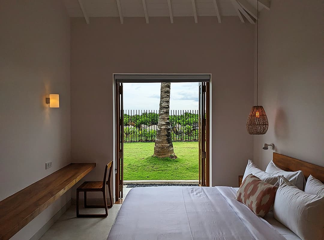 King bedroom with door open to tropical garden at Salt and Stone, Ahangama, Sri Lanka