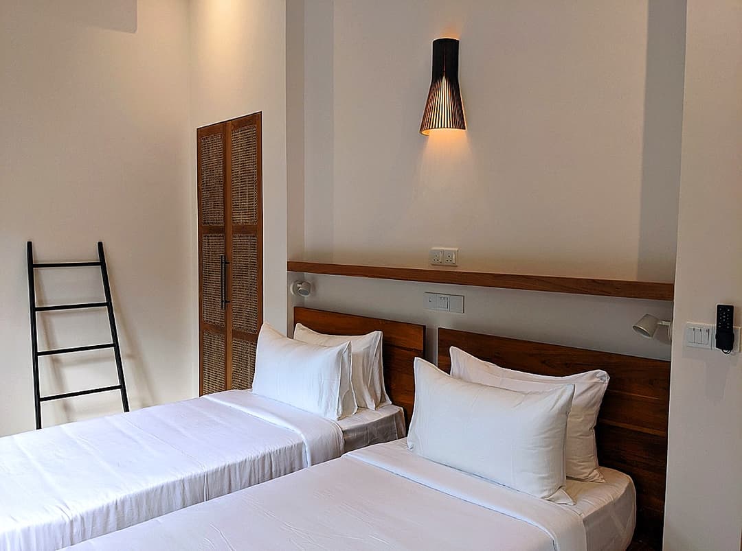 Twin bedroom with white linen and wall lamp at Salt and Stone, Ahangama, Sri Lanka
