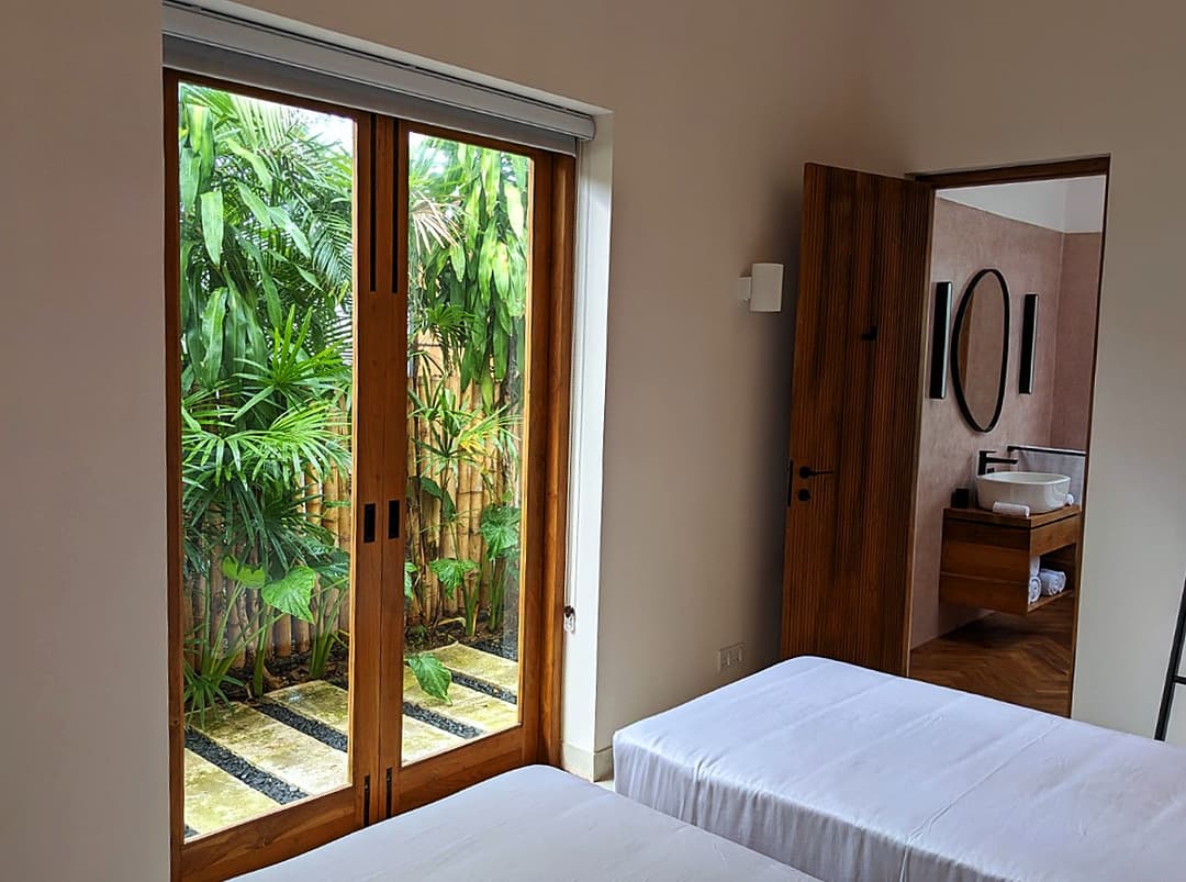 Twin bedroom with door open to tropical garden at Salt and Stone, Ahangama, Sri Lanka