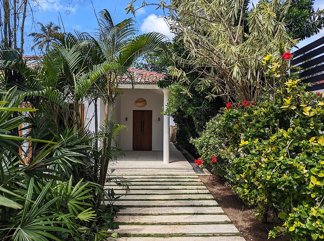 Tropical garden entrance path with flowering plants at Salt and Stone, Ahangama