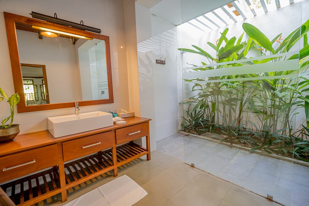 Bathroom with teak vanity and bamboo garden wall at Island Villa Ahangama, Ahangama