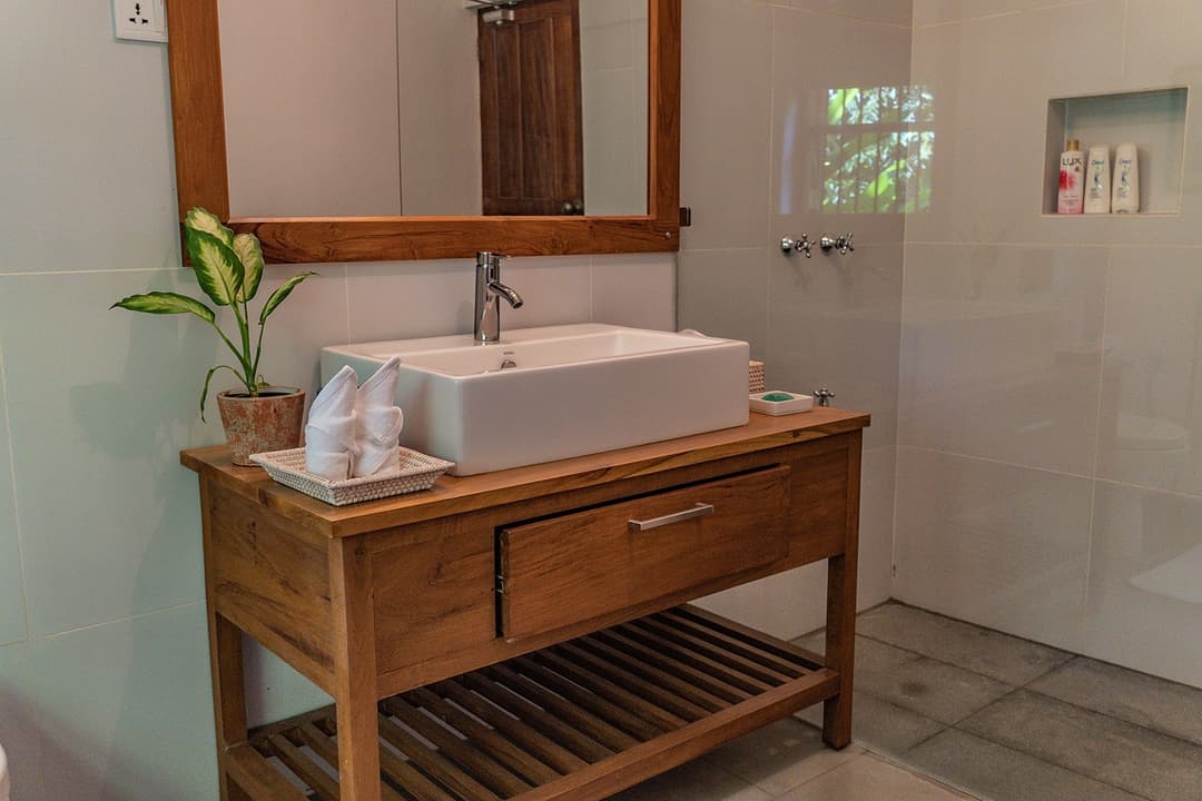 Bathroom with teak vanity and tropical plant wall at Island Villa Ahangama, Ahangama