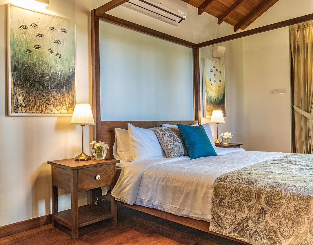 King bedroom with blue and teal cushions and wall painting at Island Villa Ahangama