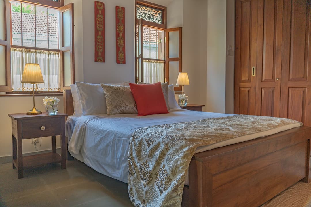 Bedroom with king bed, red cushions and timber wardrobe at Island Villa Ahangama