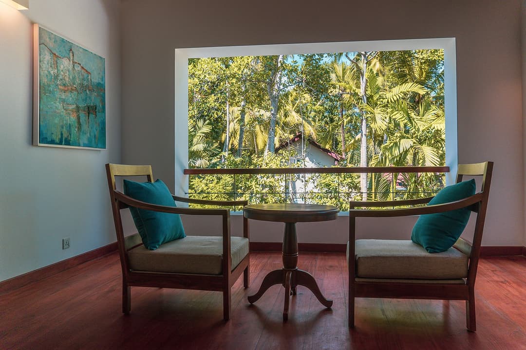 Bedroom seating area with teal chairs and garden view at Island Villa Ahangama, Ahangama