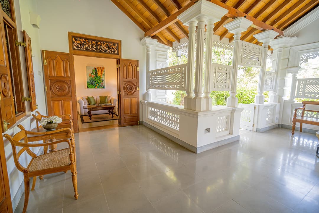 Entrance hall with carved bench and decorative door at Island Villa Ahangama, Ahangama