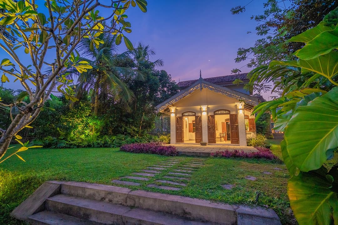 Garden house illuminated at dusk with frangipani tree at Island Villa Ahangama, Ahangama