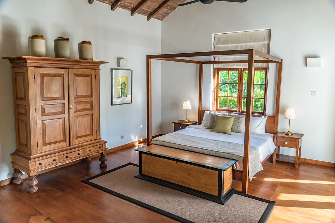 Master bedroom with four-poster bed and carved wardrobe at Island Villa Ahangama, Ahangama