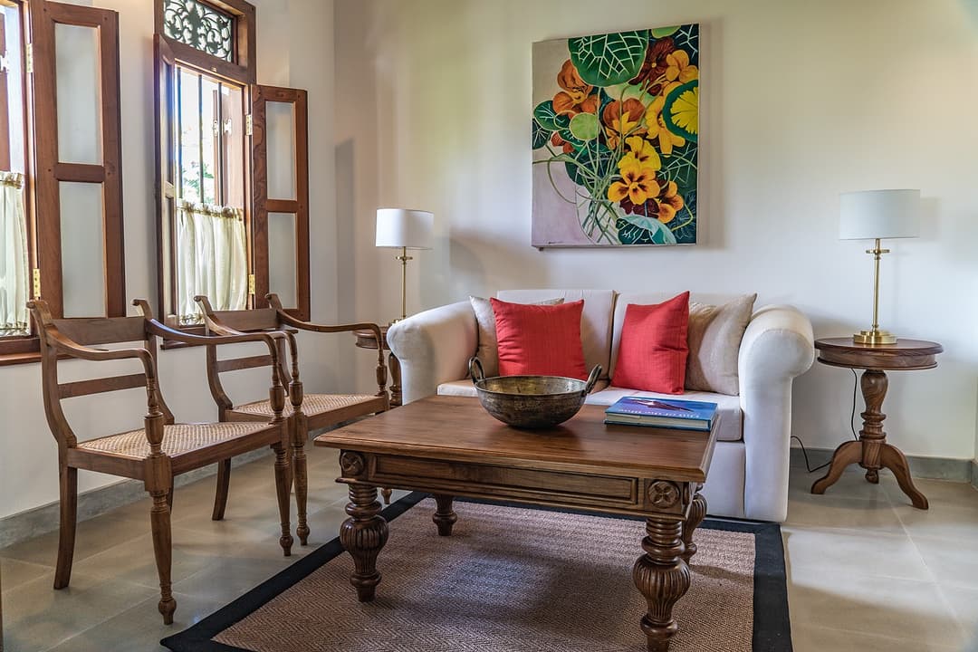 Sitting room with sofa, red cushions and colourful painting at Island Villa Ahangama