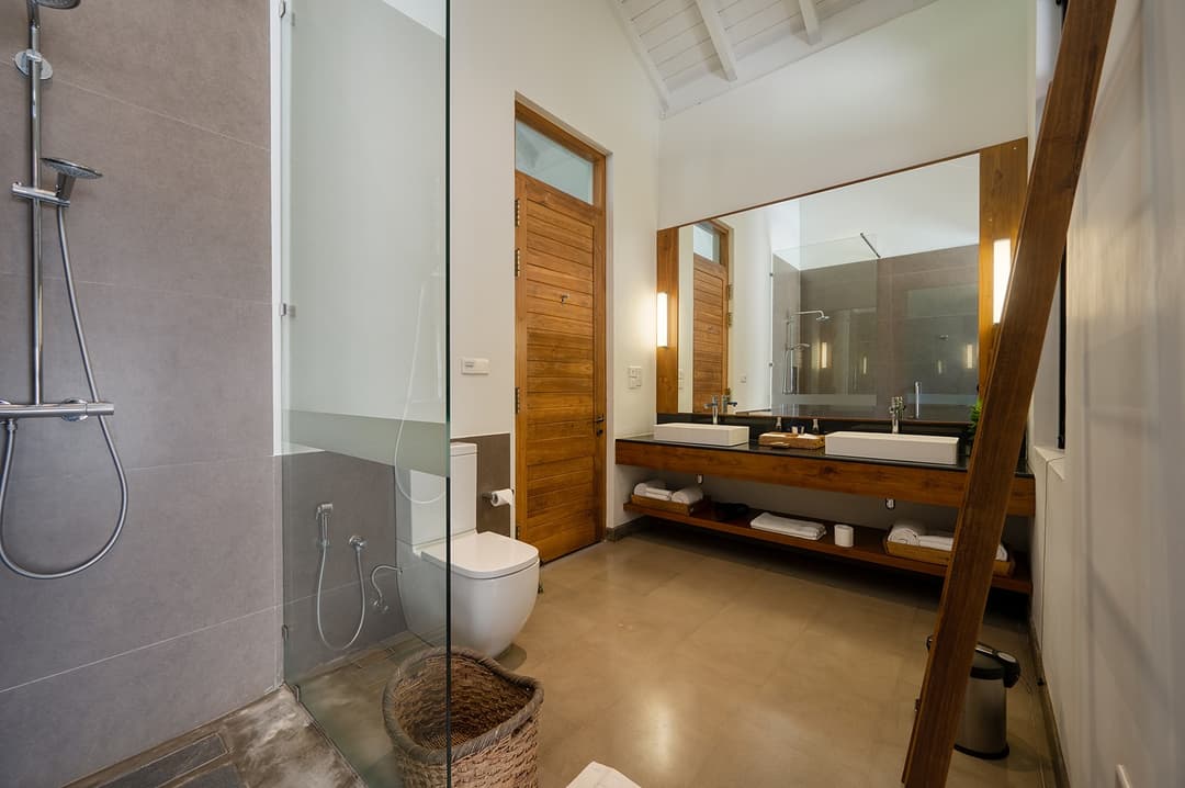 Bathroom with stone wall and timber vanity at Kirana Villa, Bentota, Sri Lanka