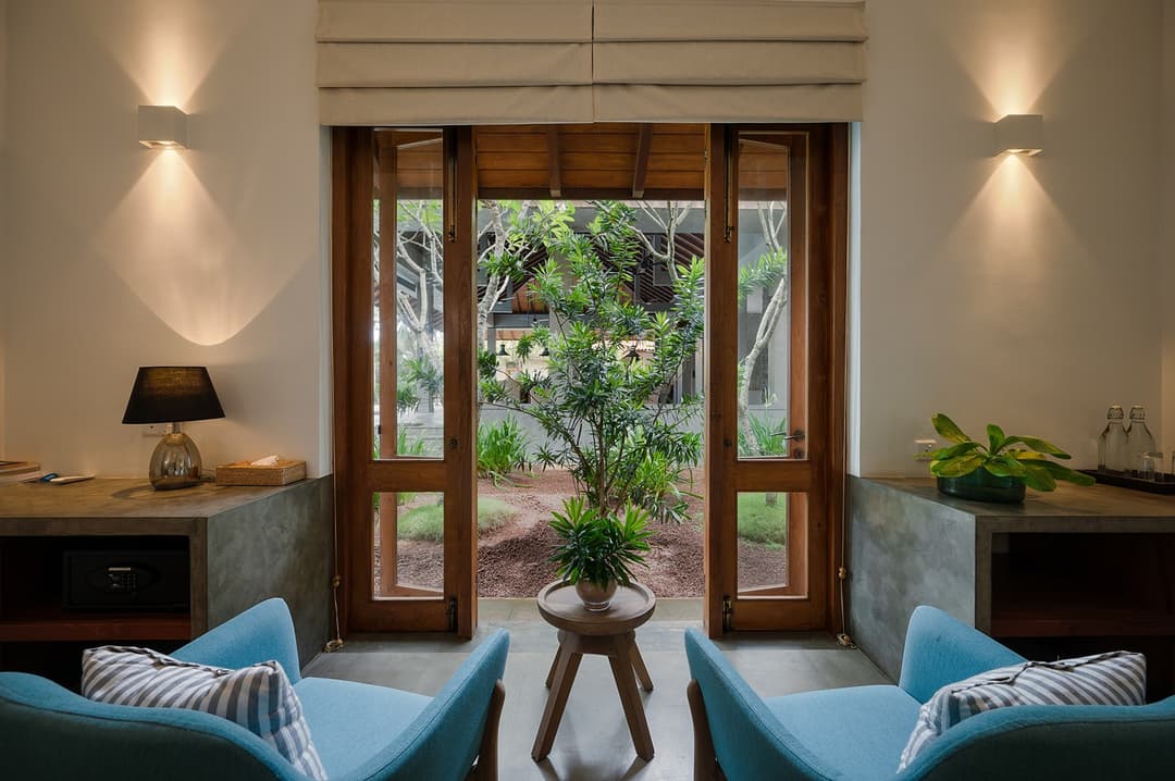 Bedroom sitting area with teal chair and stone wall at Kirana Villa, Bentota