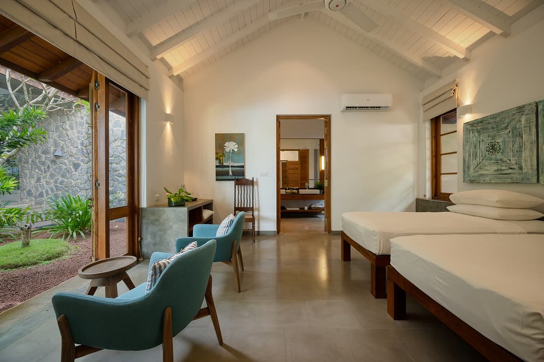 Wide bedroom with teal chairs and garden view at Kirana Villa, Bentota, Sri Lanka