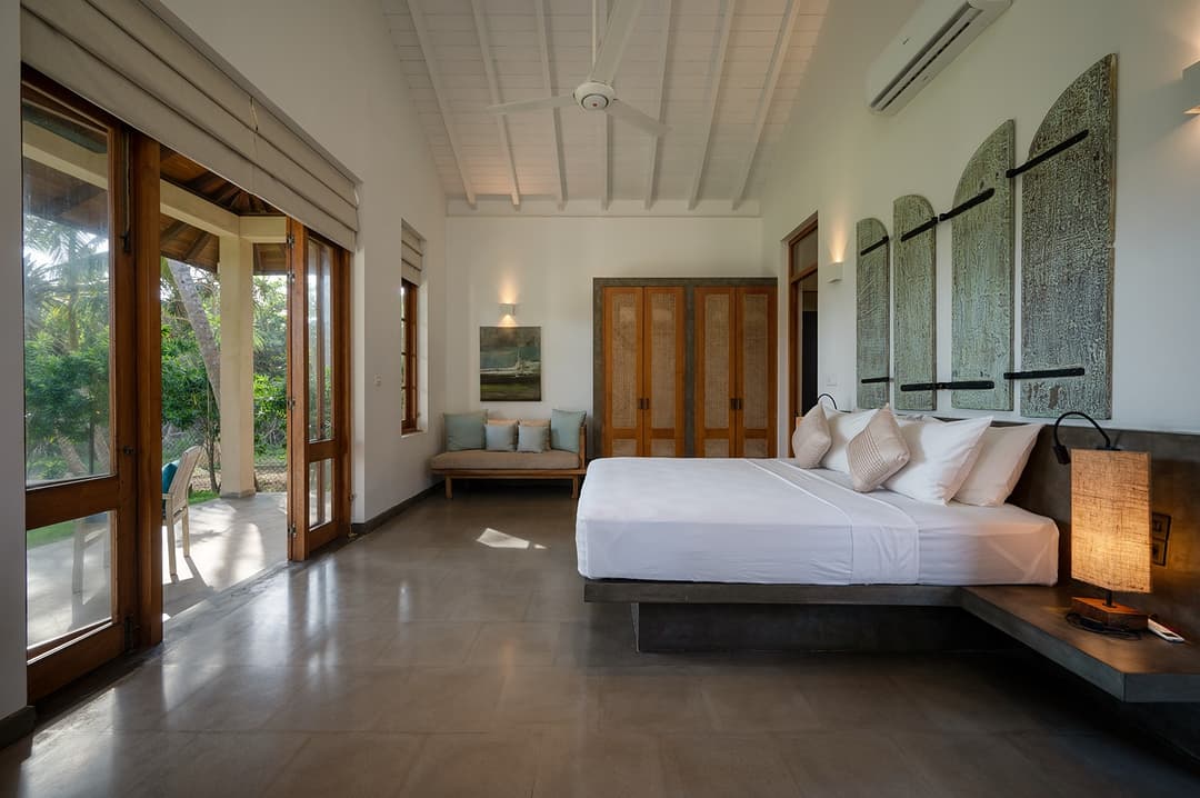 Bedroom with king bed, teal blue accents and garden windows at Kirana Villa, Bentota