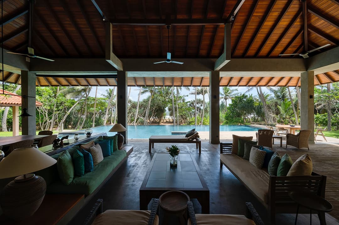 Open living pavilion with teal cushions overlooking pool at Kirana Villa, Bentota