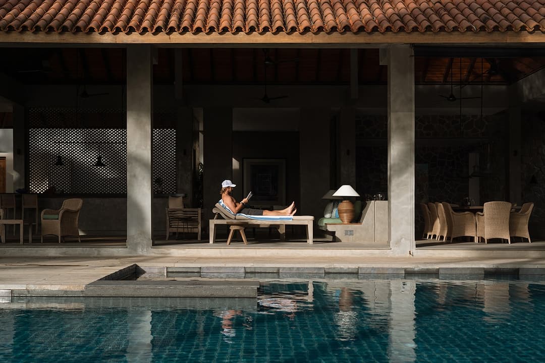 Guest relaxing in poolside pavilion with pool and palms at Kirana Villa, Bentota