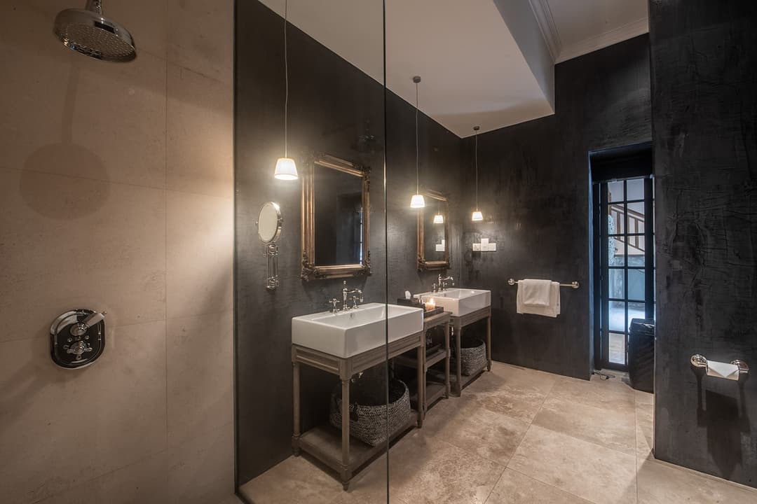 Dark bathroom with twin stone vanity basins and overhead pendant lights, No. 77 Leyn Baan