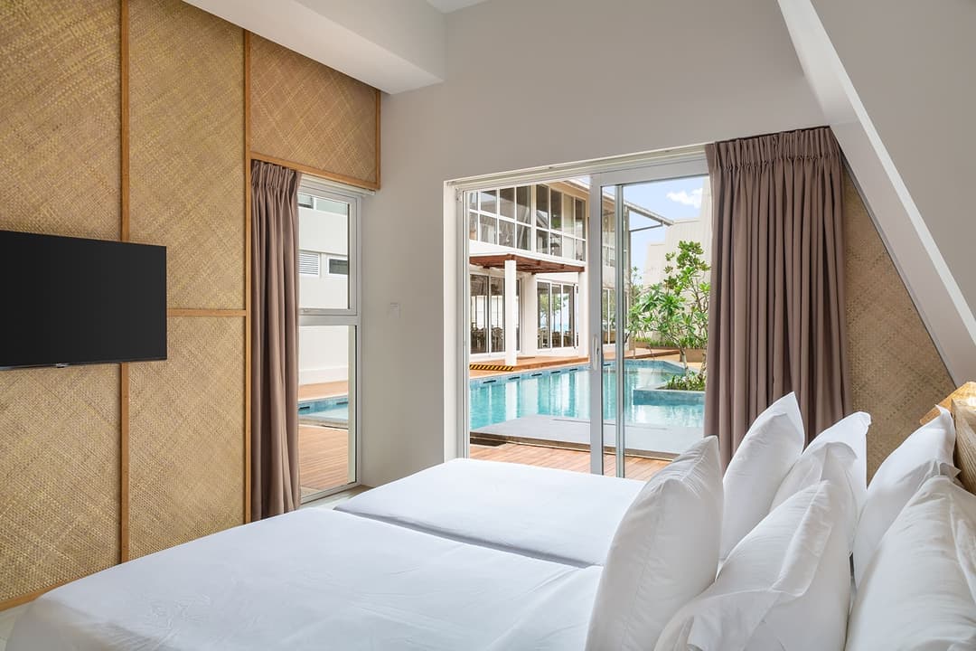 Bedroom with TV on wall and pool view window at Asaya Sands, Mirissa, Sri Lanka