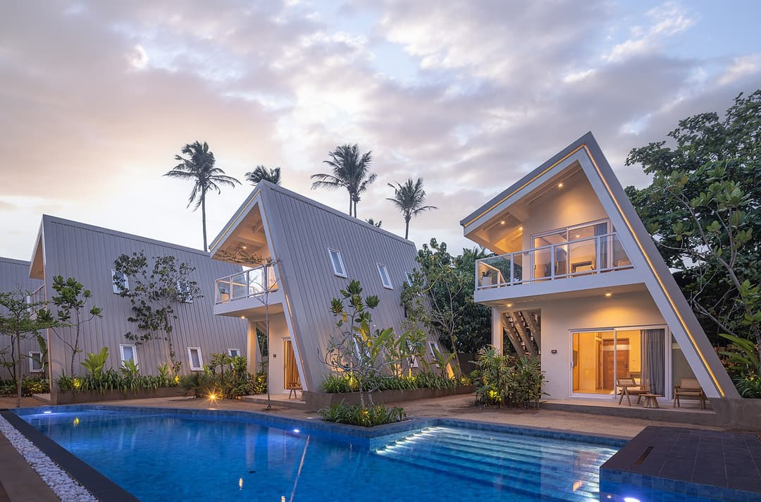 Asaya Sands Mirissa pool and A-frame chalets at dusk with palms, Mirissa, Sri Lanka