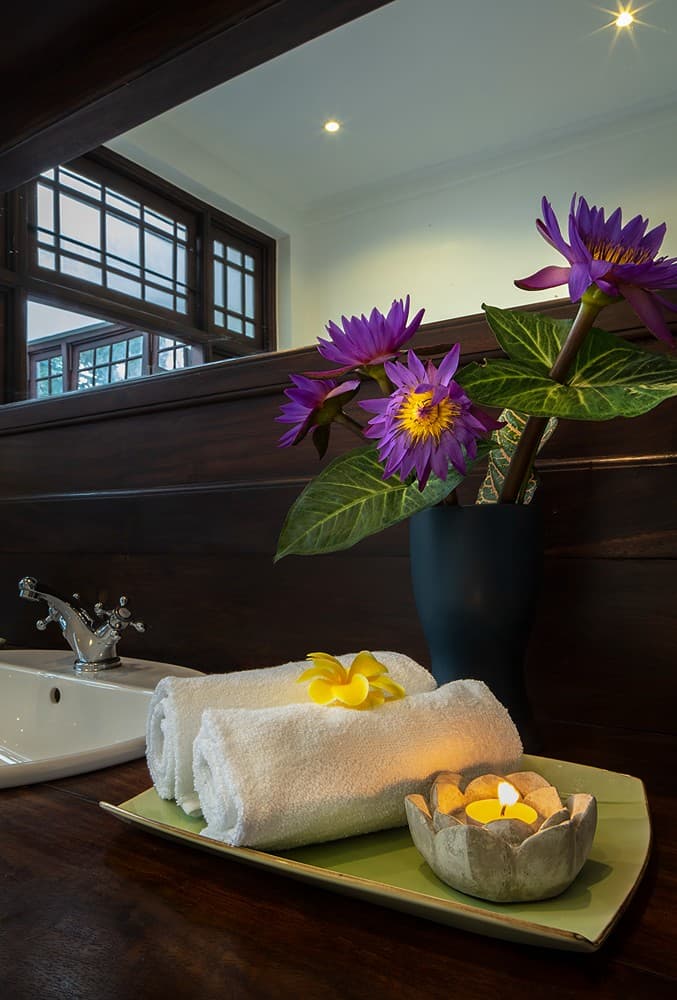 Bathroom detail with flower arrangement, towel and purple orchid, Abiman Dickwella
