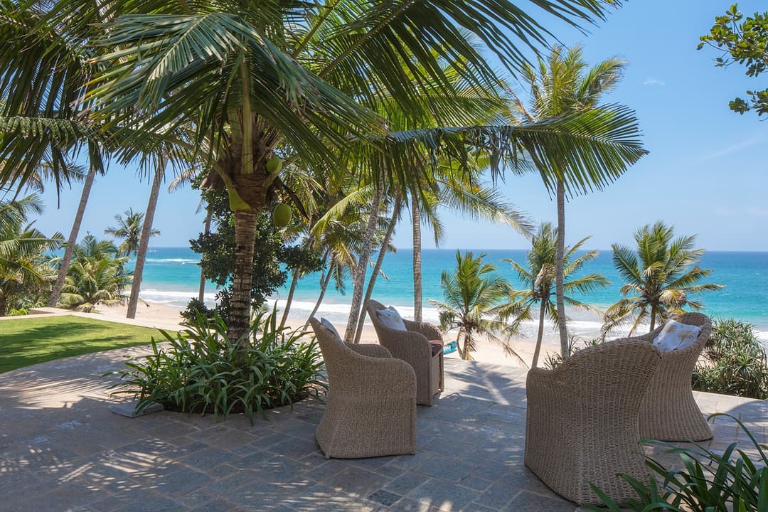 Beach seating area with chairs under palms facing Indian Ocean, Abiman Dickwella