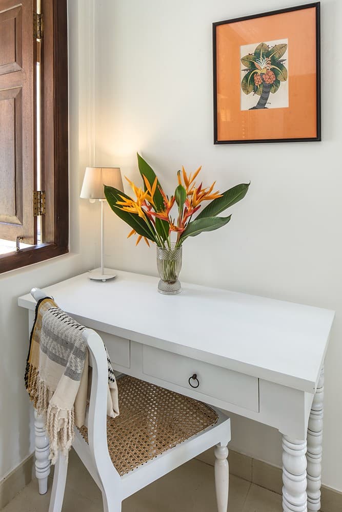 Bedroom with writing desk, orange painting and flowers at Abiman, Dickwella, Sri Lanka