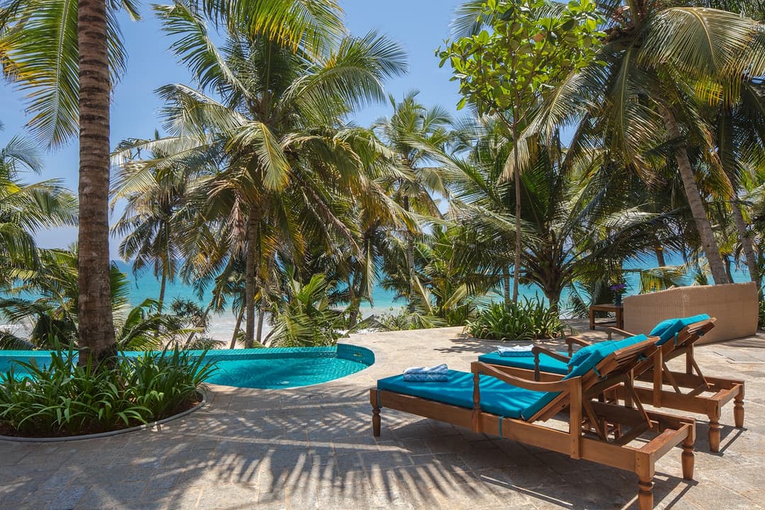 Abiman pool with sun loungers, coconut palms and ocean beyond, Dickwella, Sri Lanka