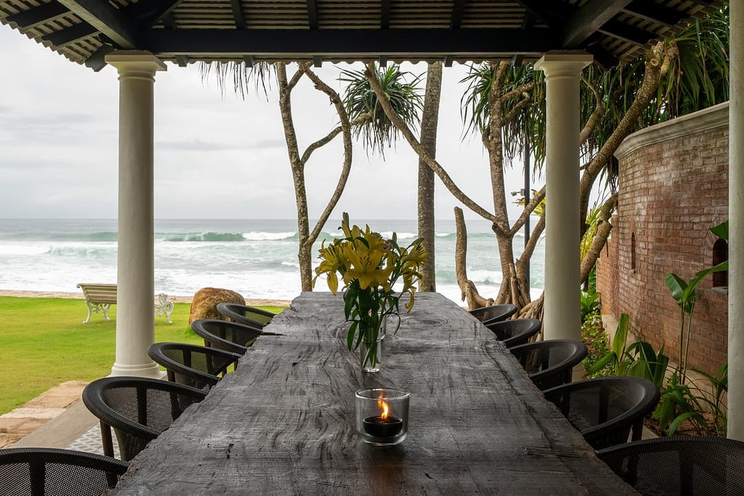 Outdoor long dining table by beach, Candella House Talpe