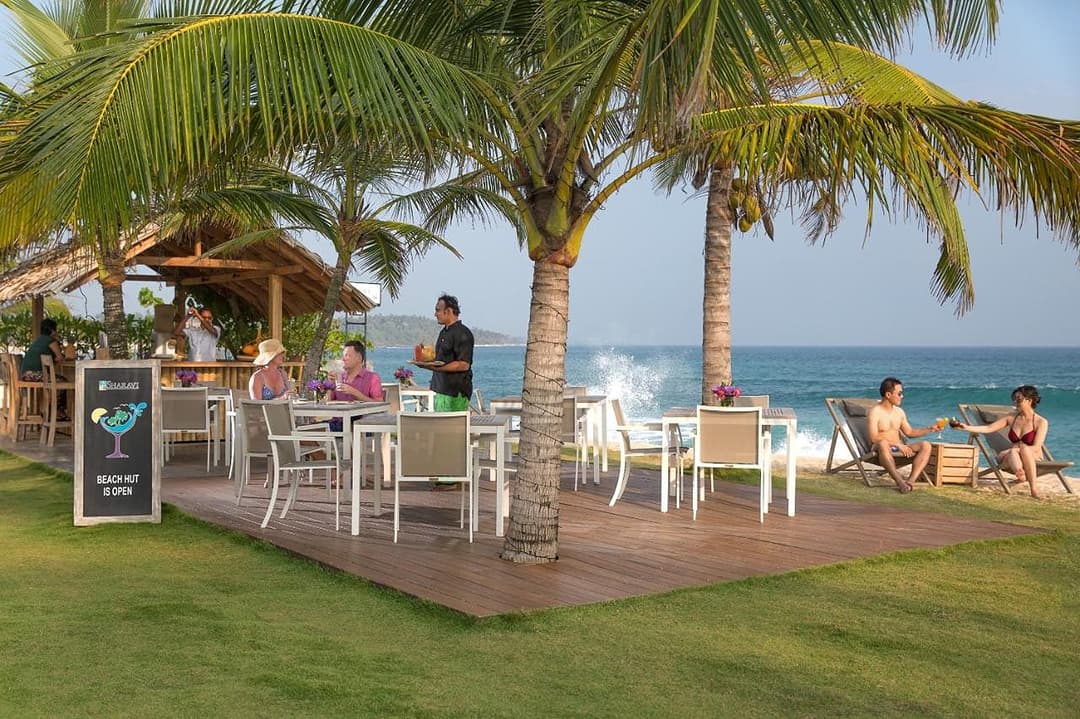 Beachfront bar with guests and palms, Sri Sharavi Mirissa