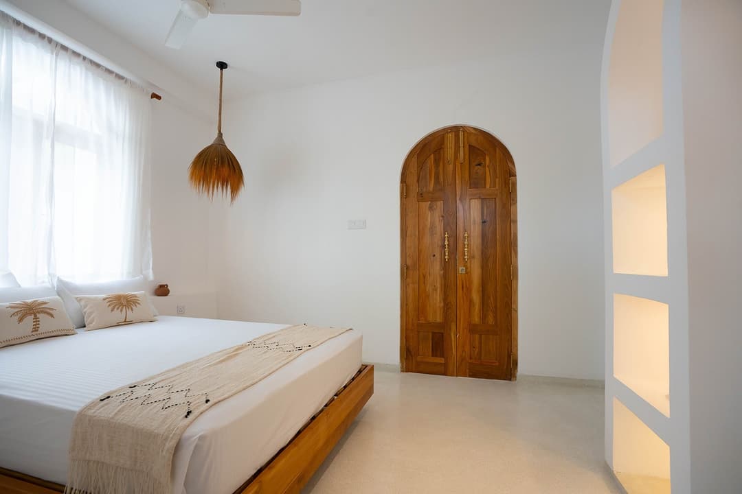 Ahangama bedroom with wood door and white bed
