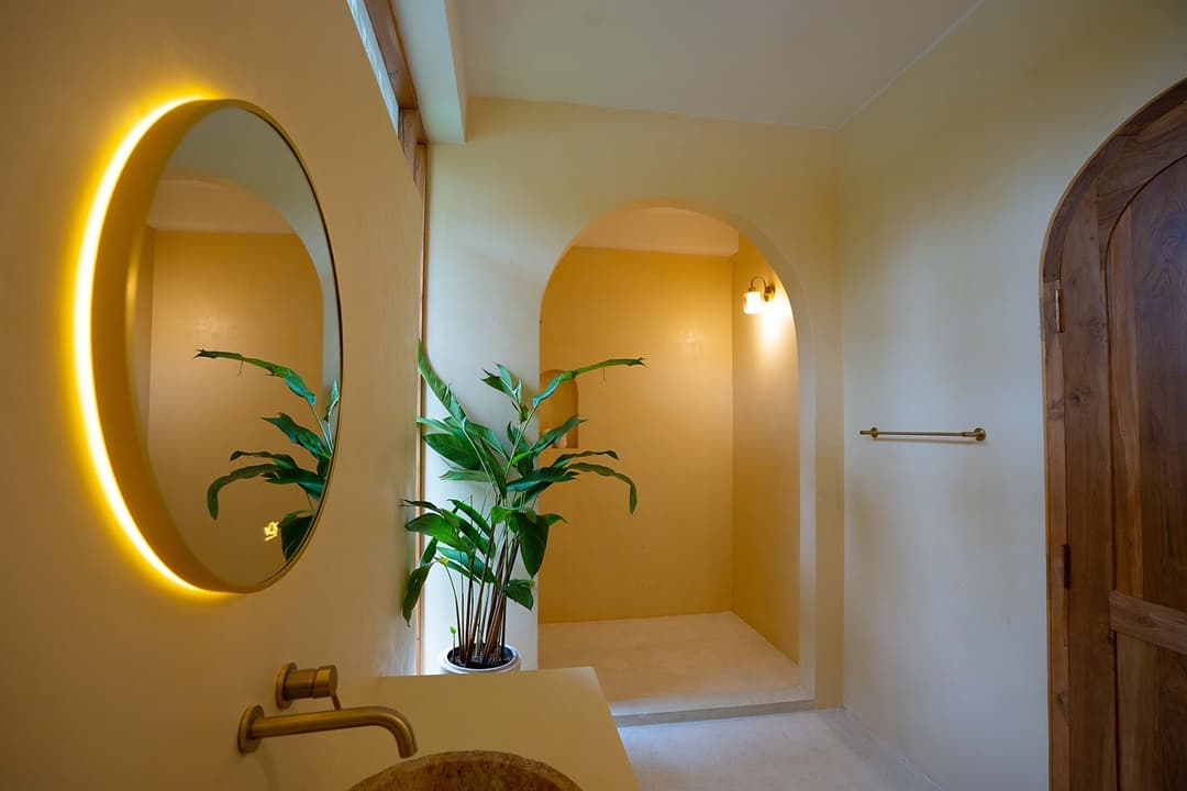 Ahangama bathroom with yellow walls and round mirror