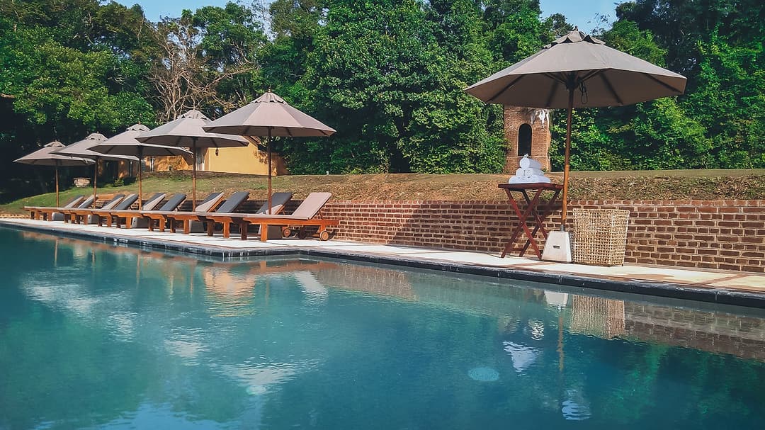 Lunuganga Bentota pool with umbrellas and garden view