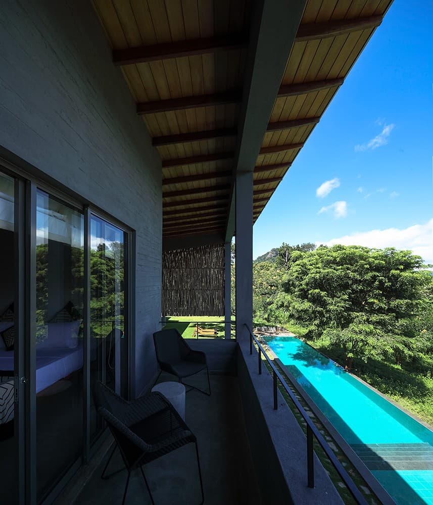 Digana bedroom with glass walls and pool view