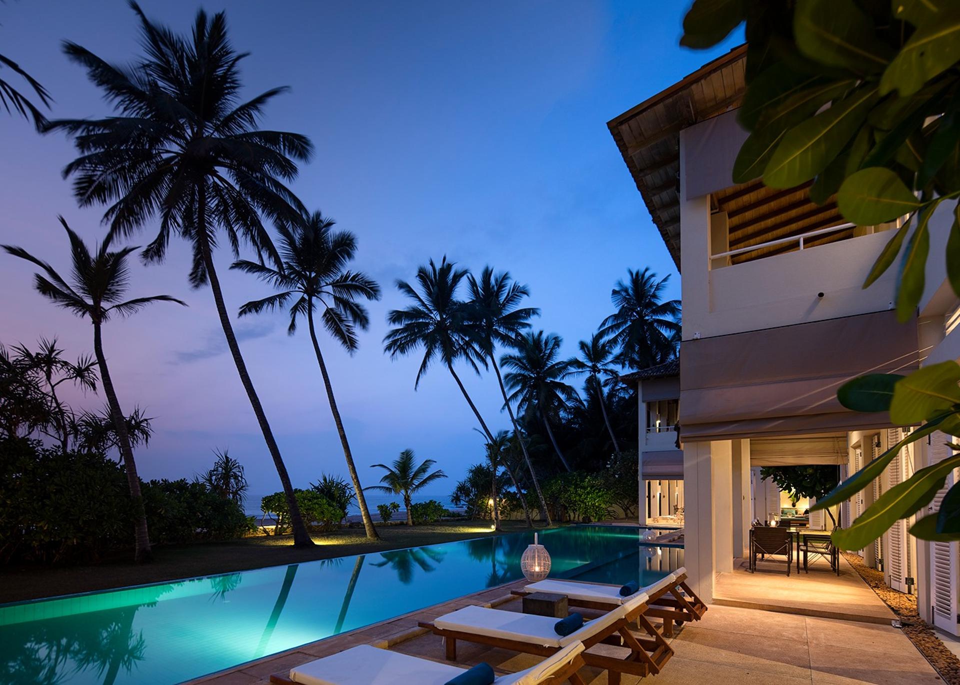Sri Villas Induruwa pool and palm trees illuminated at dusk, Induruwa Sri Lanka