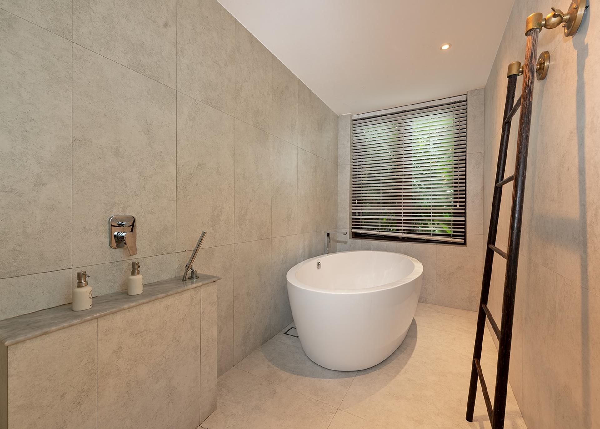 Villa ensuite bathroom with freestanding bathtub and natural stone wall finish