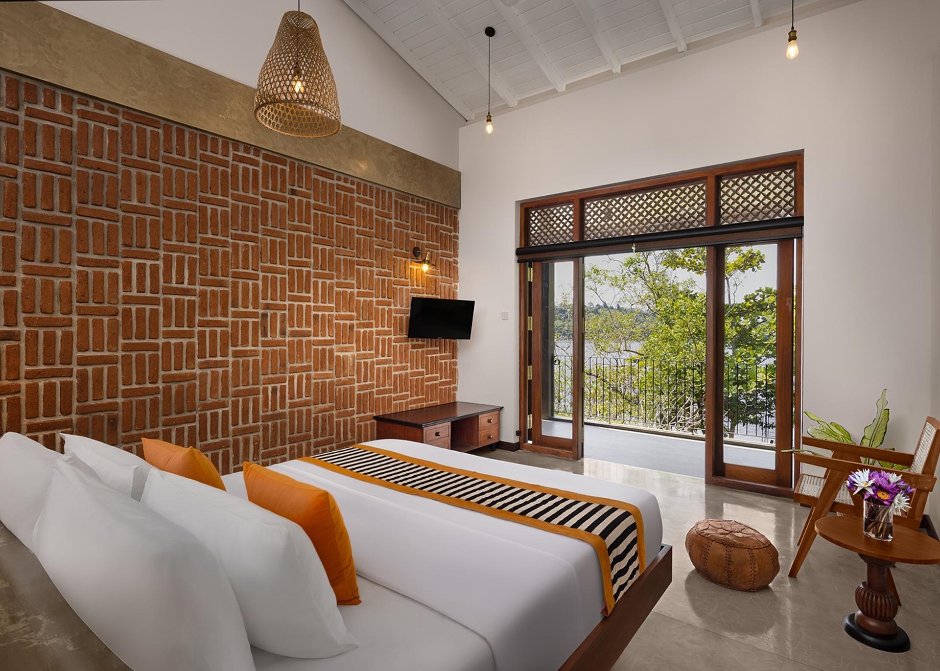 Villa king bedroom with exposed brick wall, timber furniture and garden access
